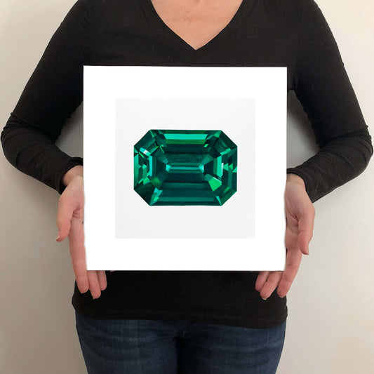 A giclée fine art print of an Emerald gemstone on a light stone background. This image illustrates the print size.