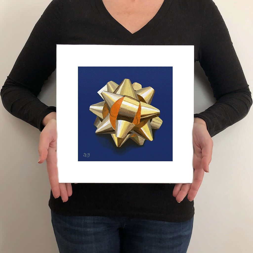 A giclée fine art print on paper of a gold metallic gift bow on a dark blue background. This image illustrates the print size.