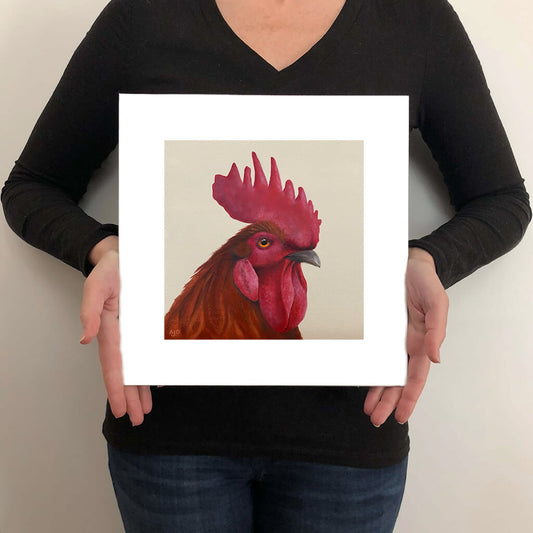 A giclée fine art print on paper of a rooster bird on a greige background. This image illustrates the print size.
