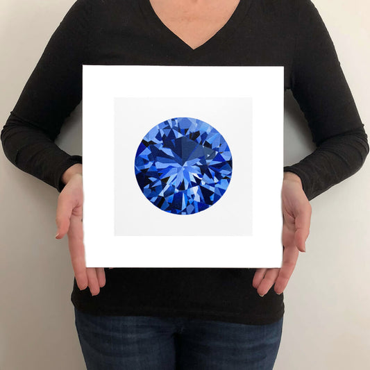 A giclée fine art print of a blue sapphire gemstone on a light stone background. This image illustrates the print size.