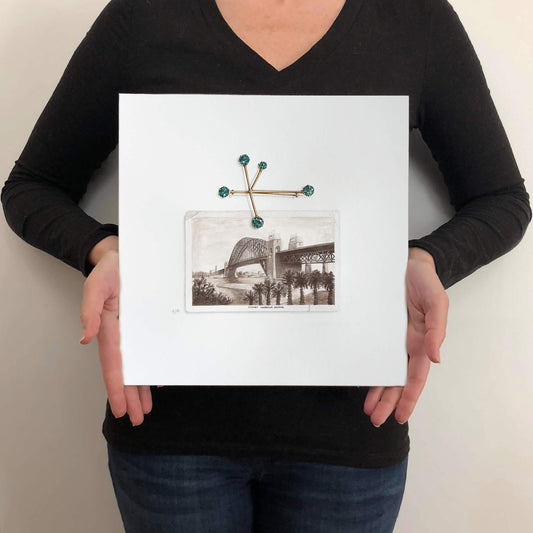 Person holding a painting on paper of Sydney Harbour Bridge and antique brooch, for scale