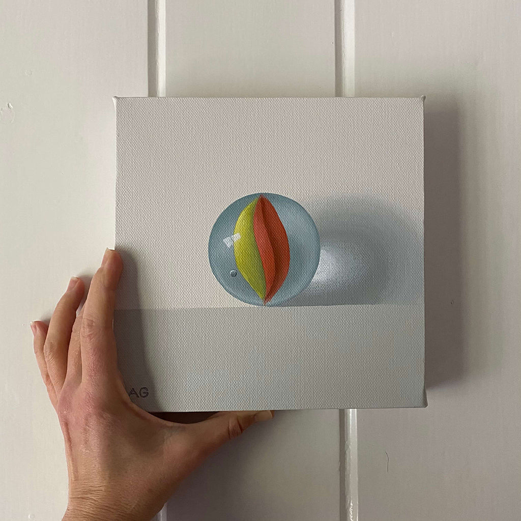 original realism acrylic painting of a yellow and red vintage glass marble toy painted by Amanda Gosse