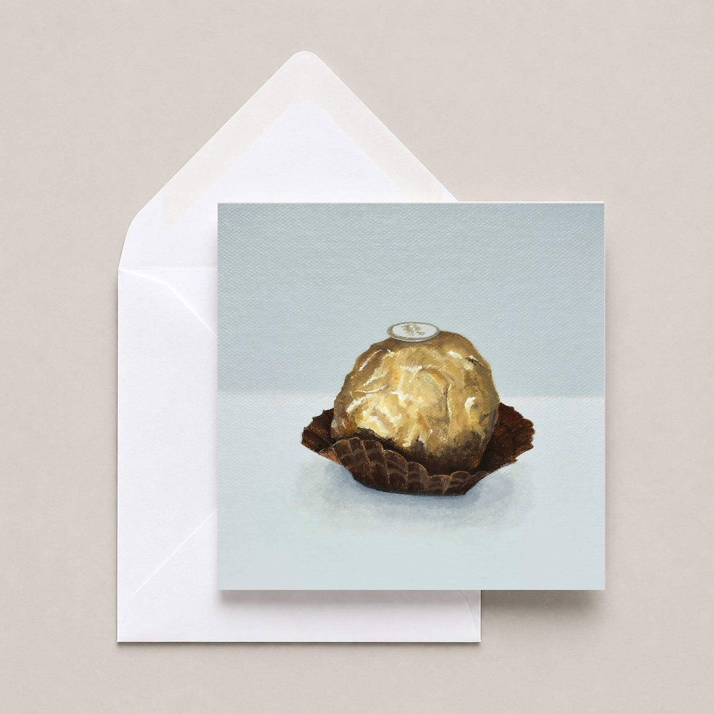 Greetings card featuring an Italian chocolate in gold foil with a white envelope on a neutral background