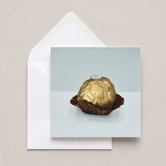 Greetings card featuring an Italian chocolate in gold foil with a white envelope on a neutral background