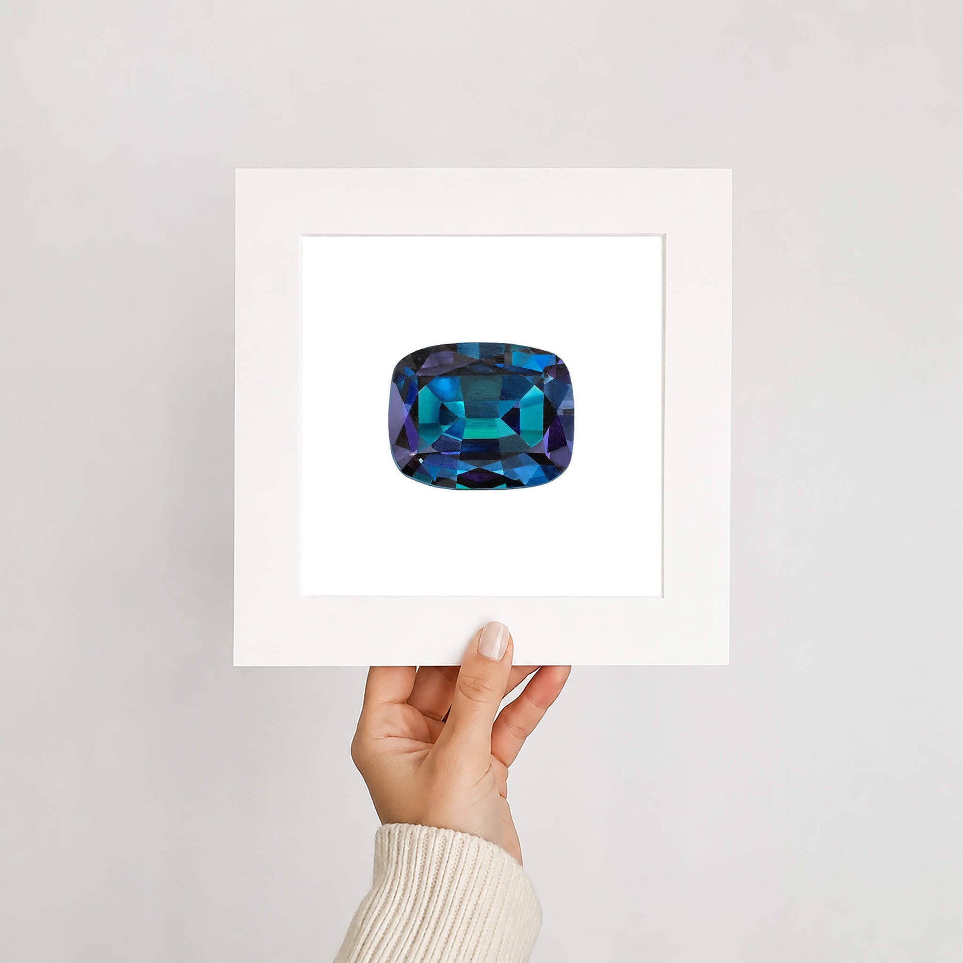 Hand holding a card with a blue gemstone on a light gray background