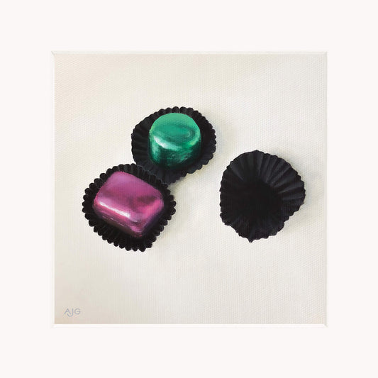 Giclée print in mount of three colourful chocolates in black casings on a white background