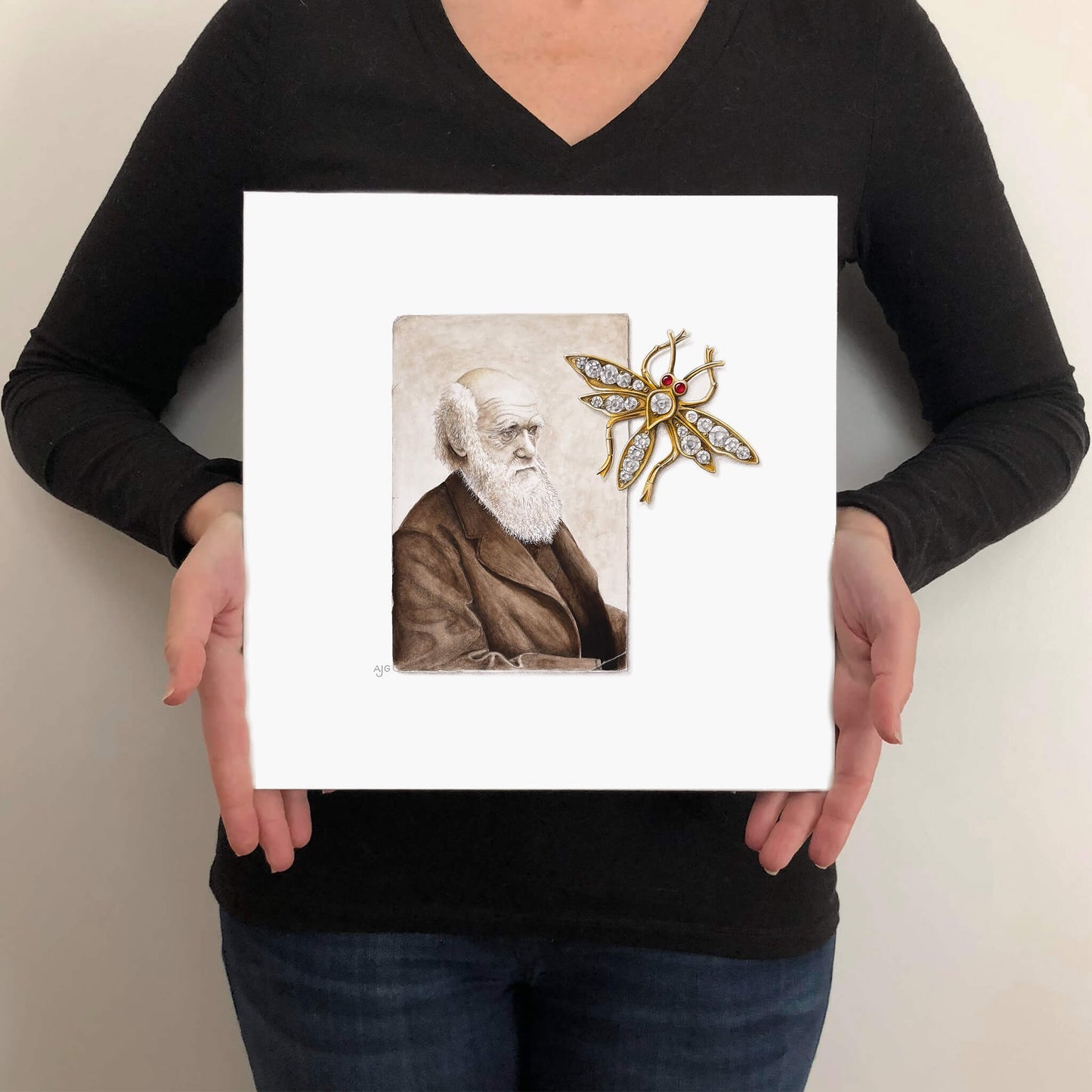Person holding a painting of a portrait and a decorative brooch on a plain background