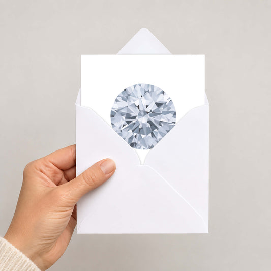 A hand holding a white envelope with a circular cutout showing a detailed, faceted diamond gemstone illustration, set against a plain light grey background.