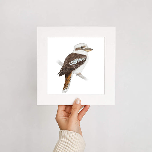 Hand holding a framed print of a kookaburra bird against a plain background