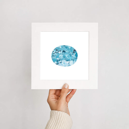 Hand holding a framed artwork with an aquamarine gemstone on a white background