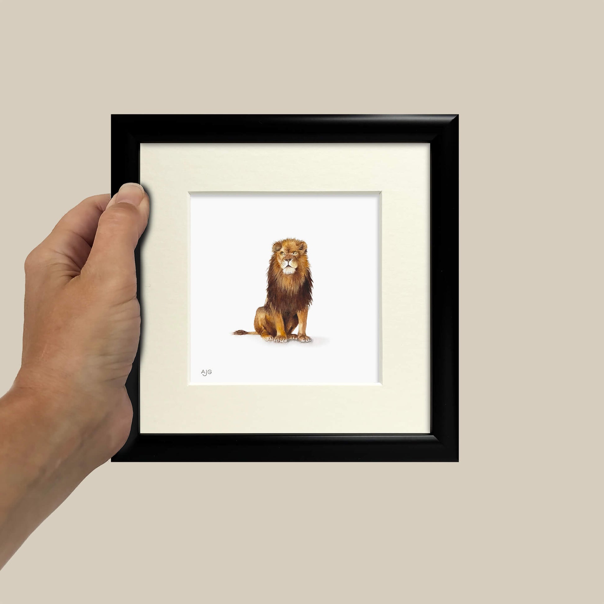 Framed artwork of a lion held by a hand against a beige background