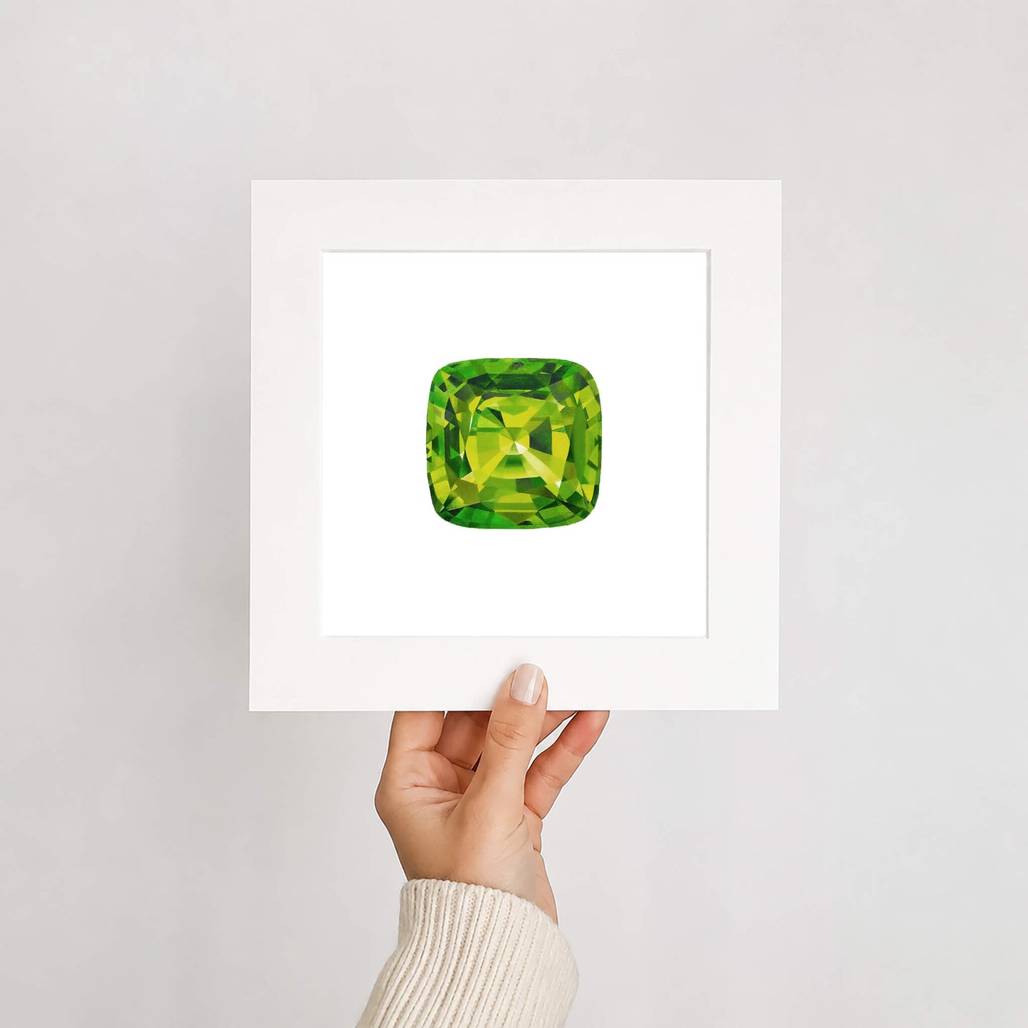Green gemstone held by a hand on a white background