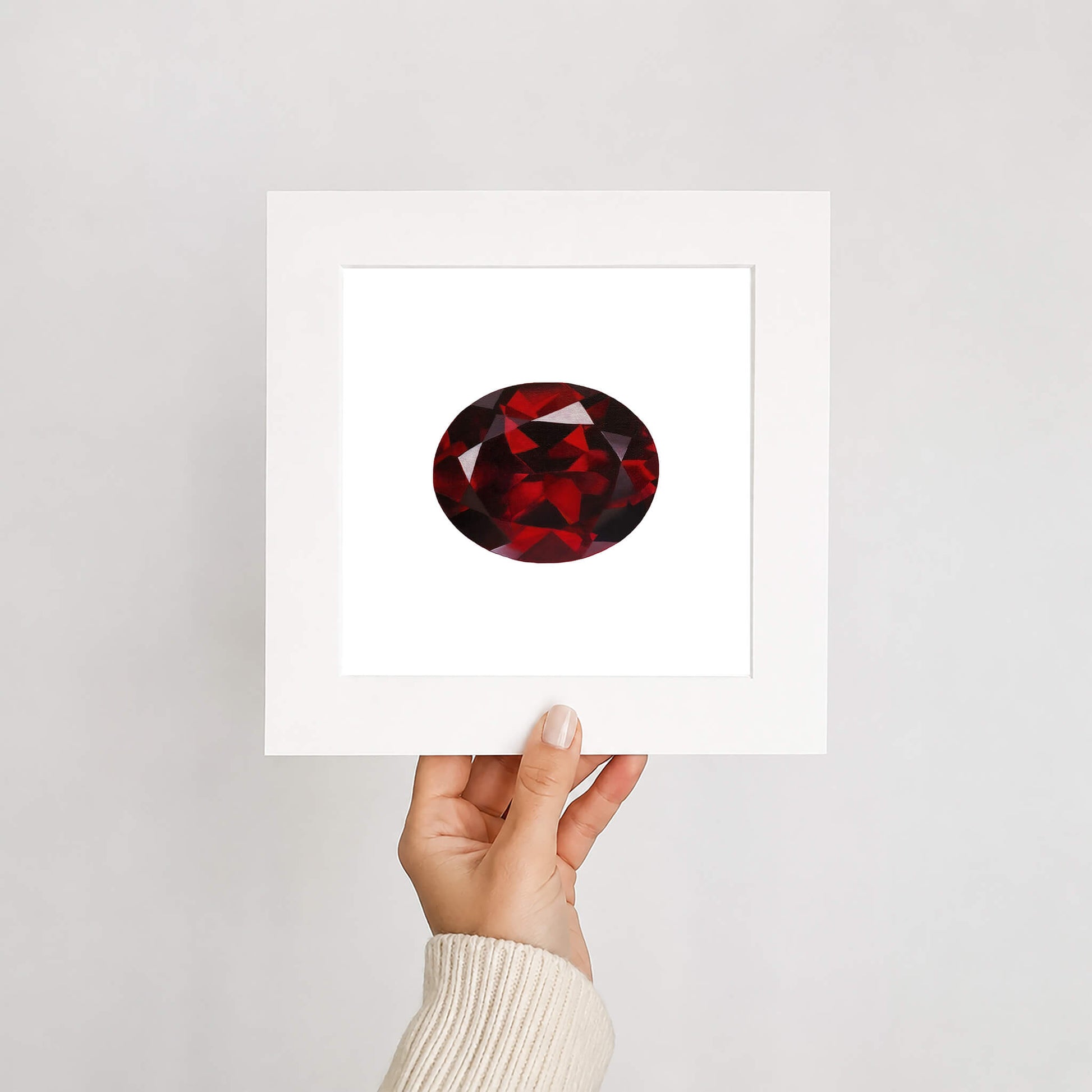 Red gemstone print held by a hand against a white background