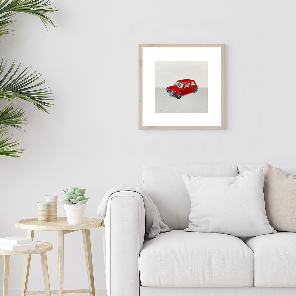 A bird giclée fine art print on paper of a red model car. Image shows the print framed and in a room setting.